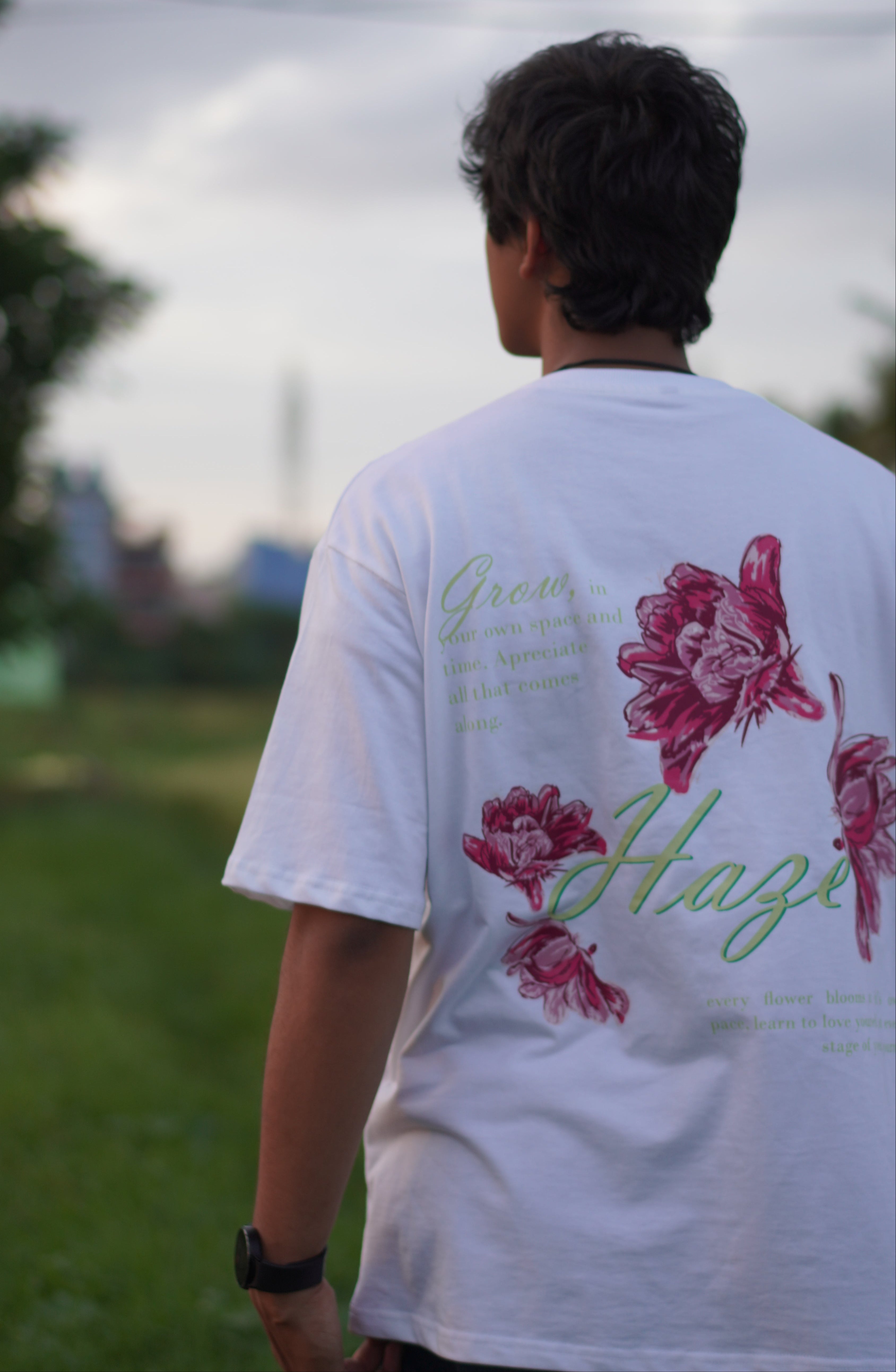 Person wearing a white shirt with floral designs outdoors